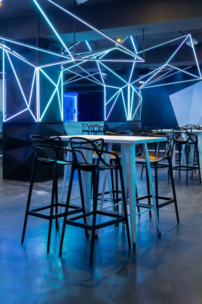 Barra retroiluminada de la Sala Singapore de NexoVenues, con mesas altas alrededor