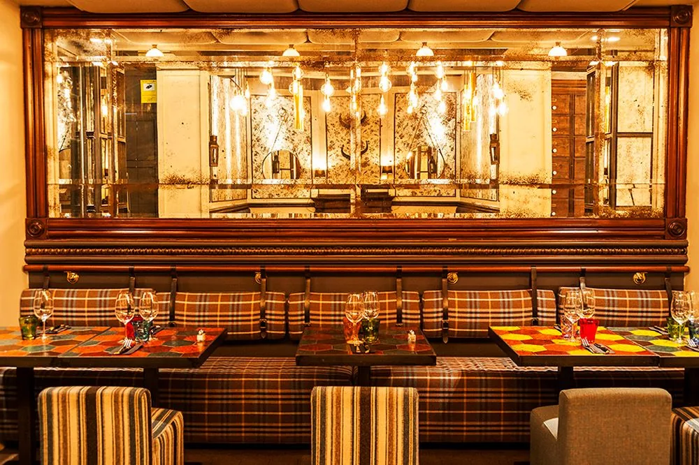Reservado del restaurante Paris de NexoVenues, con espejo envejecido y bancos tapizados